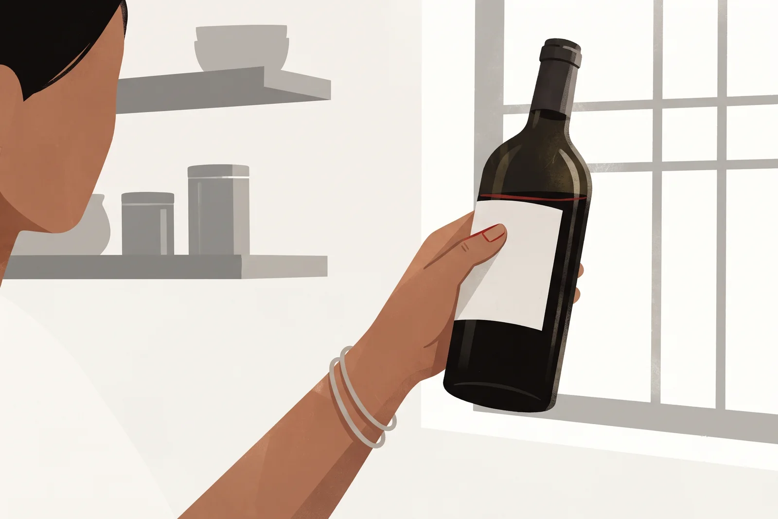 A woman's hand holds a wine bottle up to the window light, thumb against the glass, checking the level.