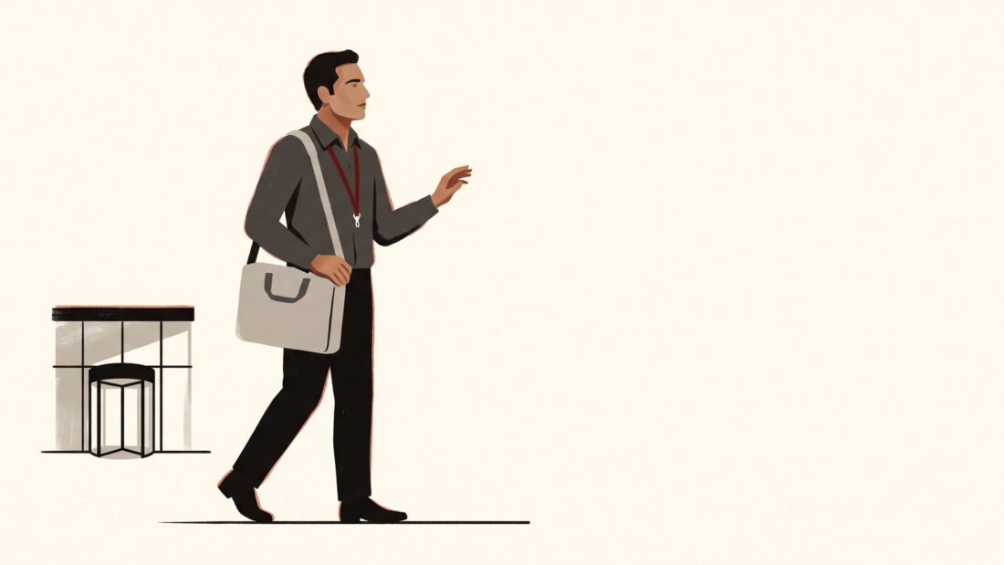 A man with a laptop bag and a red lanyard walks away from the office doors toward the point where the ground simply stops.
