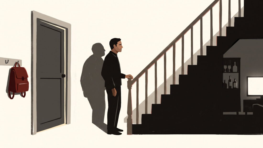 A man pauses at the foot of the stairs, a child's red school bag on the hook by the door, a drinks cabinet in the dark below.