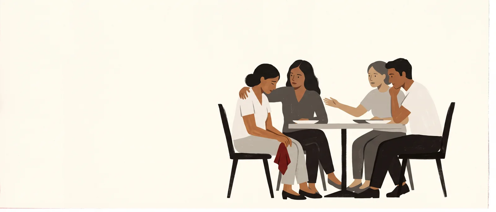 Three friends draw their chairs close around a fourth at a café table, one arm across her shoulders, nobody speaking.